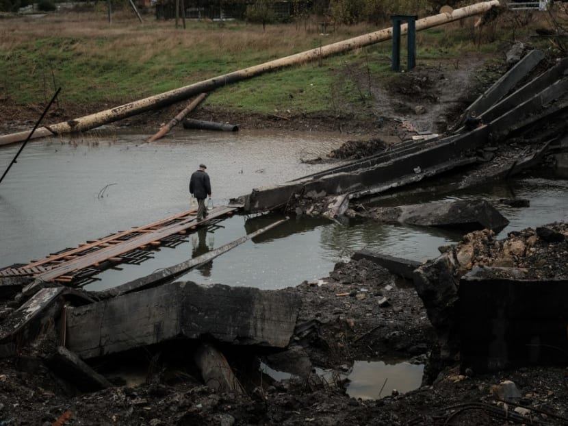 A man crosses the destroyed bridge with water bottles in the frontline town of Bakhmut in the Donetsk region on Oct 11, 2022, amid the Russian invasion of Ukraine.