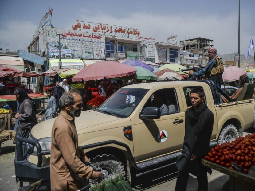 Taliban fighters on a pick-up truck move around a market area, flocked with local Afghan people at the Kote Sangi area of Kabul on Aug 17, 2021, after Taliban seized control of the capital following the collapse of the Afghan government.