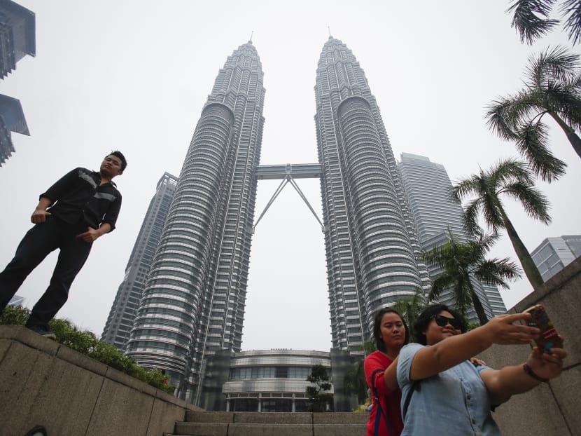 Tourists take souvenir photographs against one of Malaysia's landmark building, Petronas Twin Towers slightly obscured with haze in Kuala Lumpur, Malaysia on Oct 5, 2015. Photo: AP