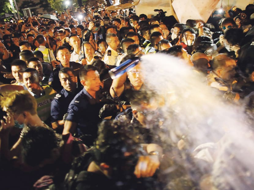 Police officers use pepper spray in the early hours of yesterday to stop protesters from blocking a major road near Mr Leung’s office. Photo: REUTERS