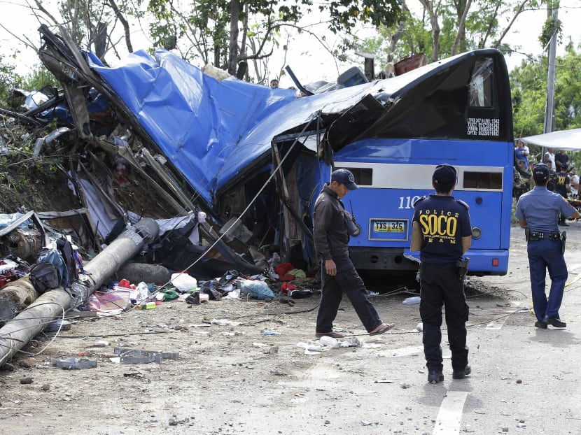 Police investigators standing by the wreckage of a bus that killed more than a dozen passengers as it lost it's brakes on a downhill road in Tanay, Rizal province east of Manila on Feb 20, 2017. Photo: AP