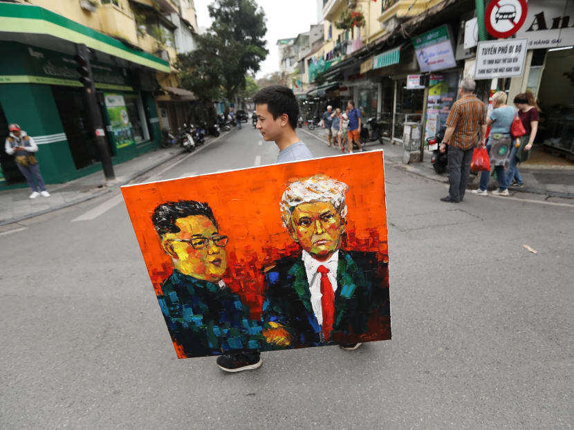 A man walks while holding a painting of North Korean leader Kim Jong-un and US President Donald Trump ahead of the North Korea-US summit in Hanoi, Vietnam, on Wednesday, February 27, 2019.