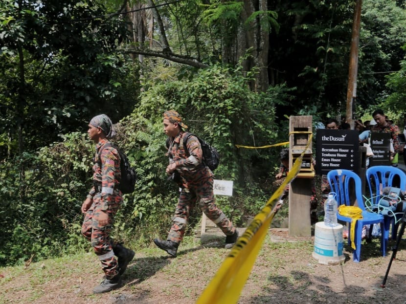 Members of the search team are seen entering an area cordoned by police after the discovery of a body in the jungle near Seremban August 13, 2019.