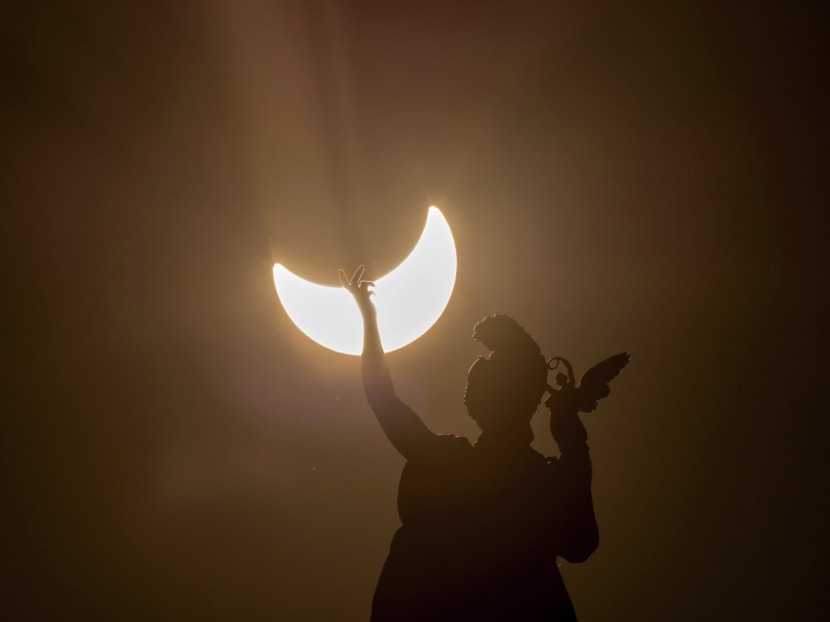 A partial solar eclipse is visible over a statue located at the rooftop of Austrian Art History Museum in Vienna on March 20, 2015. Photo: AFP