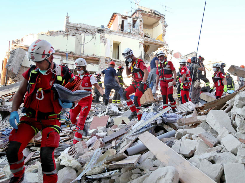 Rescuers walking through rubble in Amatrice. The village normally has a population of about 2,500, but it was packed with visitors when the quake struck as people slept in the early hours of Wednesday. Photo: Reuters