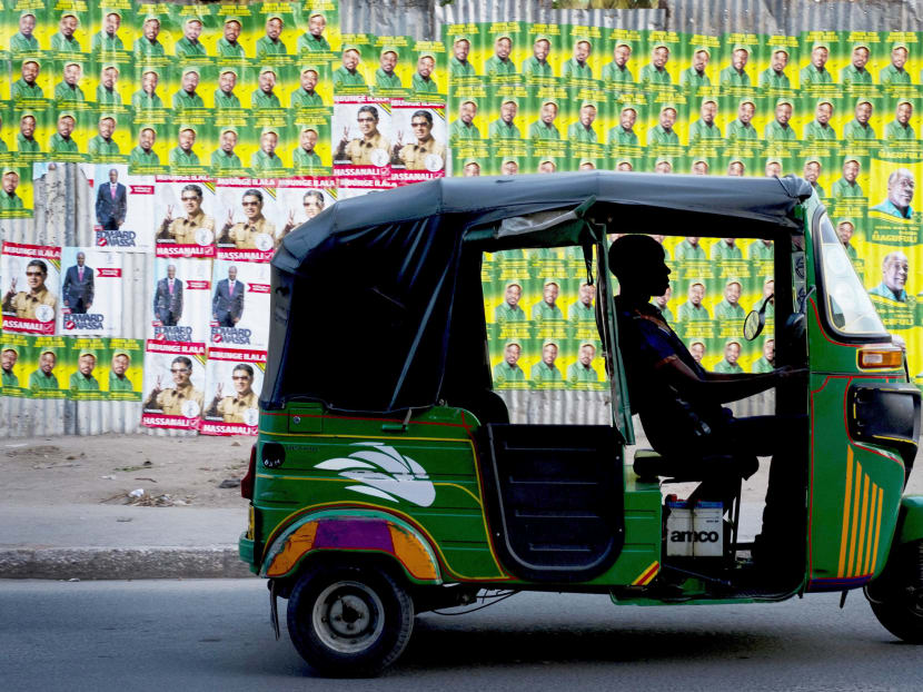 A bajaji (tuk-tuk) driver waits in traffic next to election posters in Dar es Salaam on Oct 20, 2015. Photo: AFP