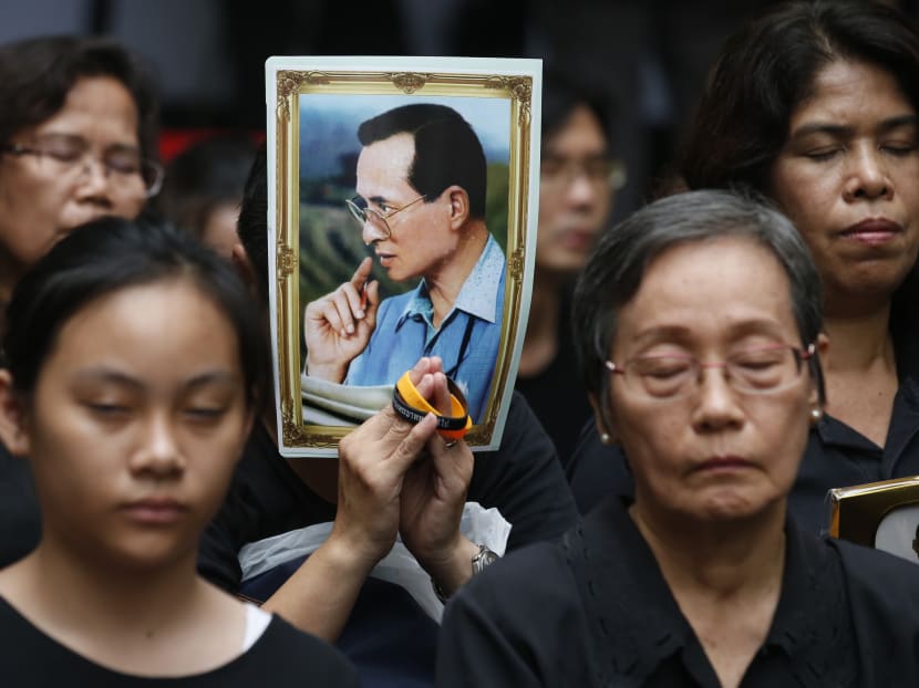 Thai mourners hold a portrait of the late Thai King Bhumibol Adulyadej during a moment of silence at Siriraj Hospital where he died in Bangkok, Thailand. AP file photo