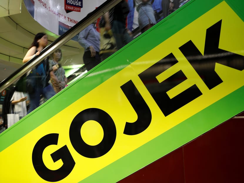 Commuters pass by a Gojek advertisement in Singapore on March 4, 2019.