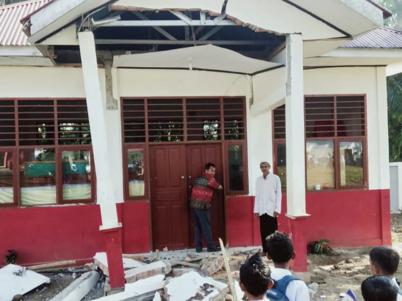 Residents inspect a building damaged by a magnitude 6.2 earthquake at Kajai village in West Pasaman on Feb 25, 2022.