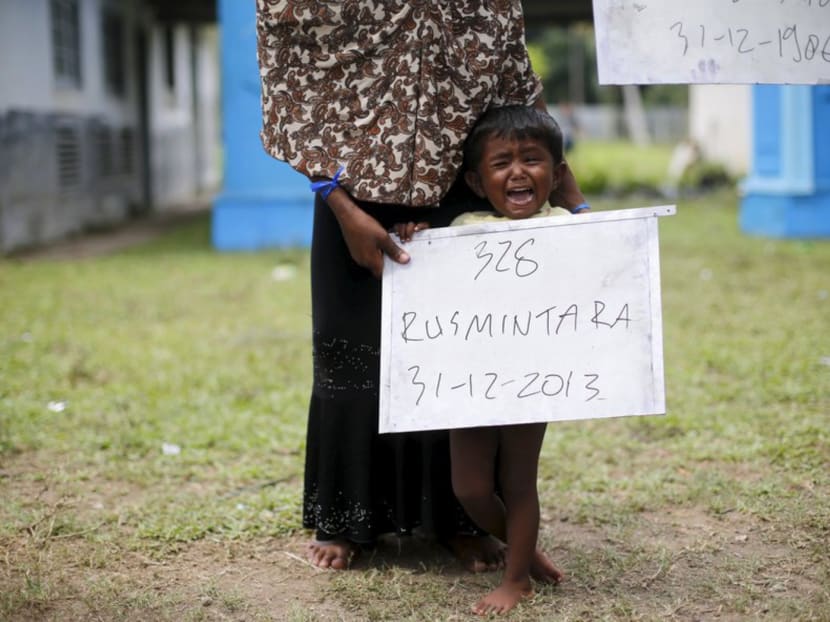 A Rohingya mother holding a placard with her child during photographs for immigration identification purposes yesterday in Aceh Timur. Photo: REUTERS