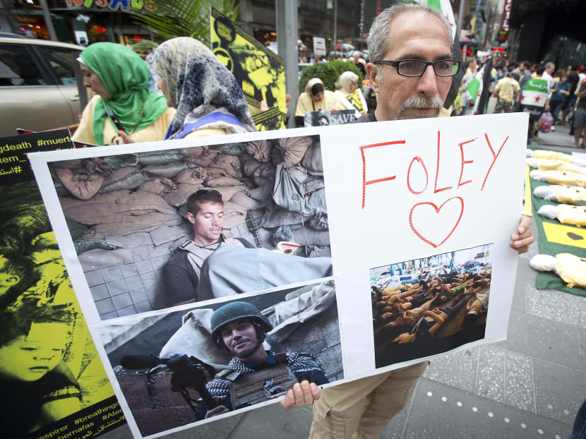 A man holds up a sign in memory of US journalist James Foley during a protest against the Assad regime in Syria in Times Square in New York, Aug 22, 2014. Photo: Reuters