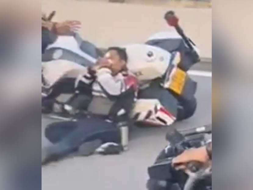 A screengrab from the YouTube channel of SG Road Vigilante shows a traffic police officer leaning against a motorcycle and clasping his face.