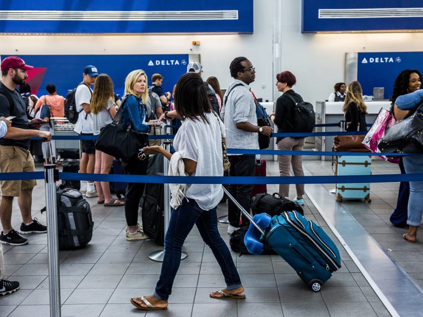 Travelers wait in line at the Delta Air Lines Inc. ticket counter inside LaGuardia Airport in New York. Photo: BLOOMBERG