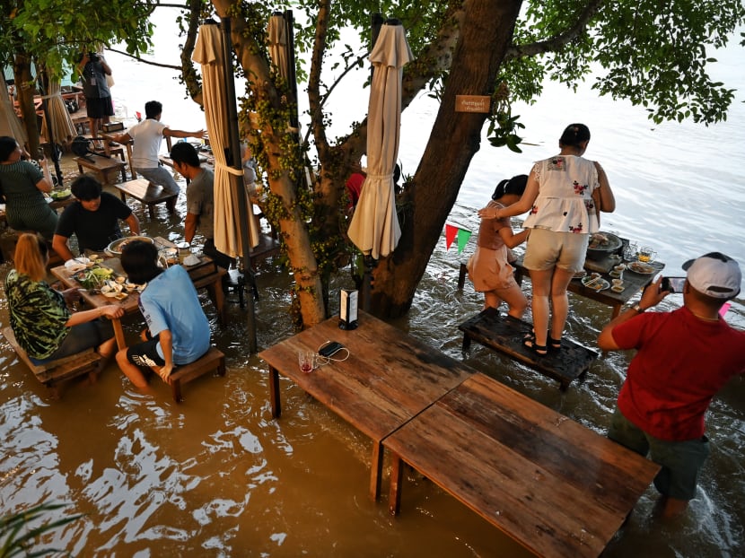 People standing up while dining at the Chaopraya Antique Cafe, as flood water from the Chao Phraya River surges into the restaurant, in Nonthaburi province, north of Bangkok, on Oct 7, 2021.