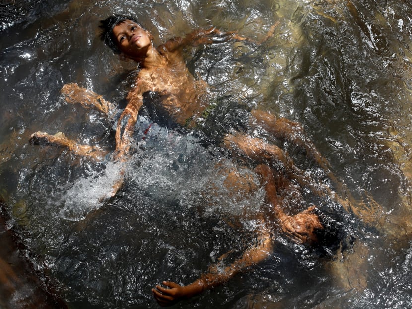 Boys cool themselves off in the waters of a tube well on a hot summer day at a field in New Delhi, India on Thursday, July 1, 2021.