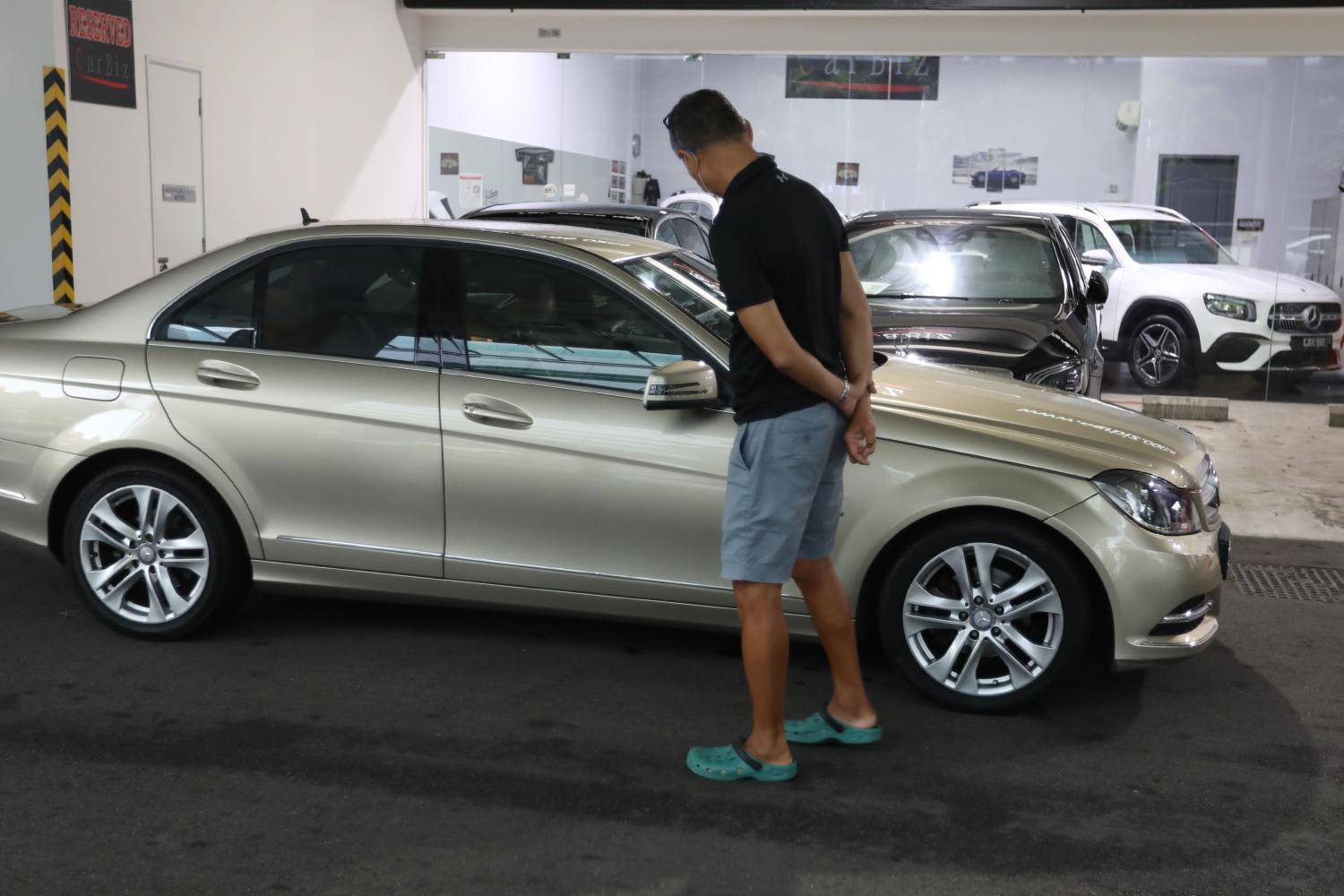 A man looking at a car that was being sold in a showroom in Singapore.