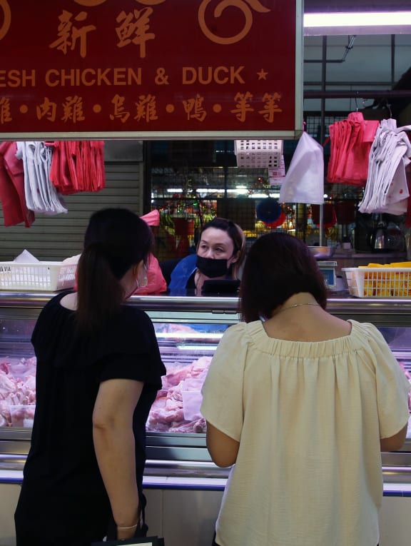 Customers buying chicken from a stall selling fresh poultry at a wet market in Vista Point, Woodlands.