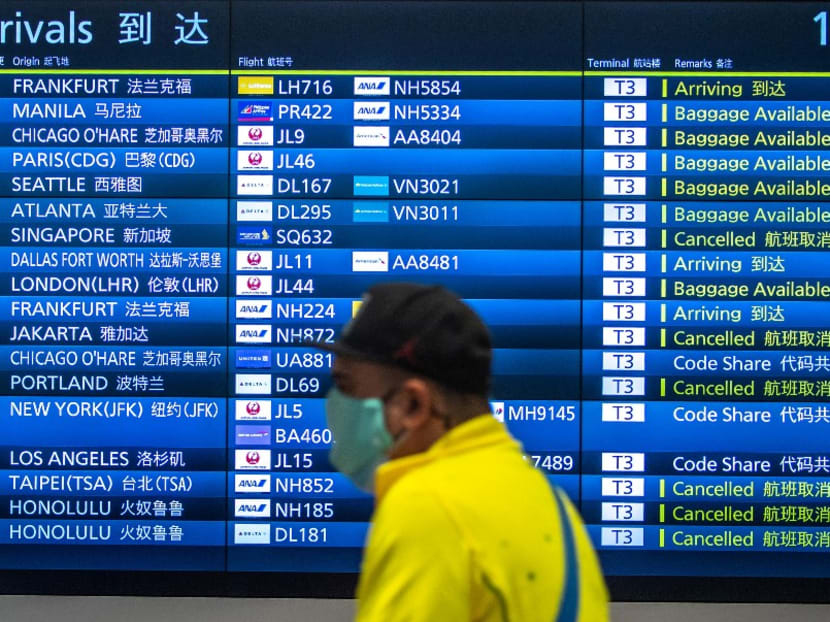 A passenger walks past a board showing international flight arrivals at Tokyo's Haneda international airport on March 2, 2022. 