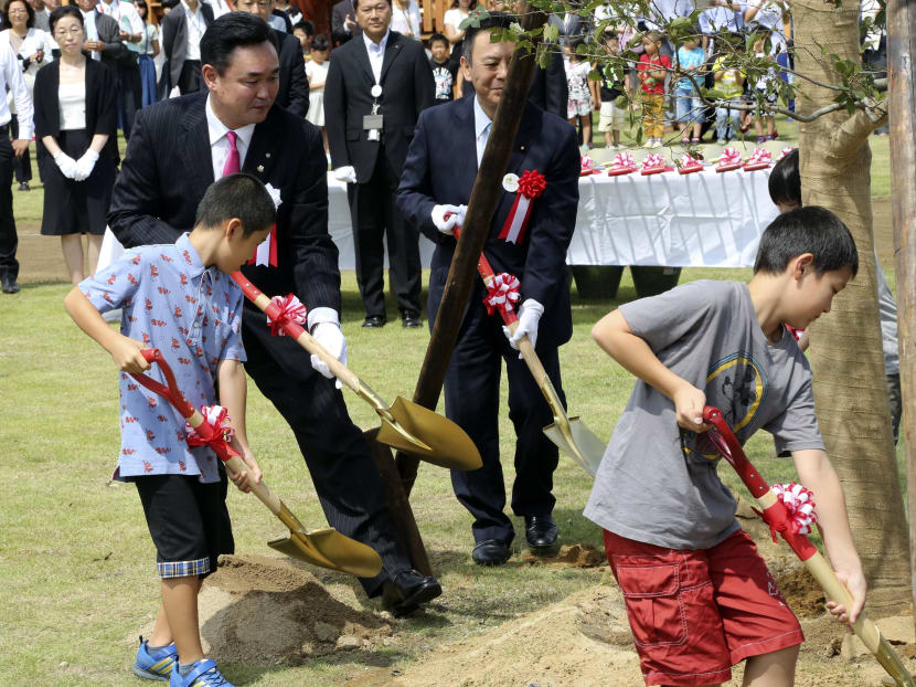 Noraha town mayor Yukiei Matsumoto, left,  plants a tree with children of Naraha residents during a installation event in Naraha, Fukushima, northern Japan, Saturday, Sept. 5, 2015. Photo: AP