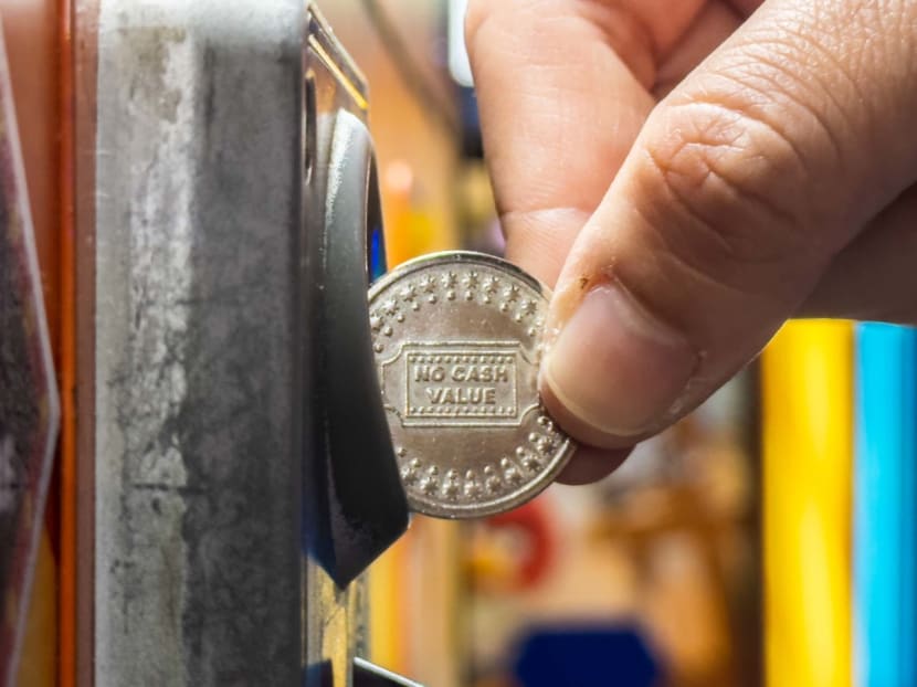 A patron playing a "coin-pusher machine" at a games arcade. A patron playing a "coin-pusher machine" at a games arcade.