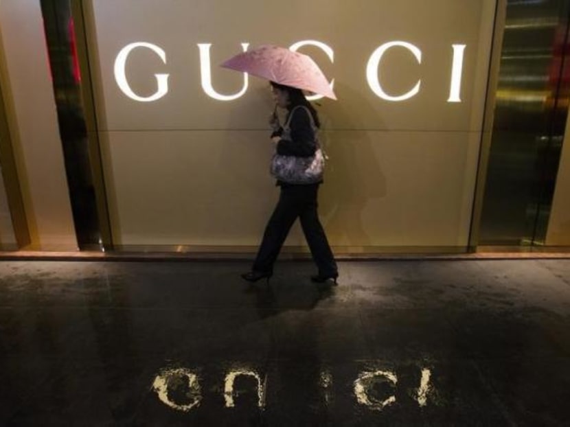 A woman walks past a company logo of a Gucci boutique. Photo: Reuters