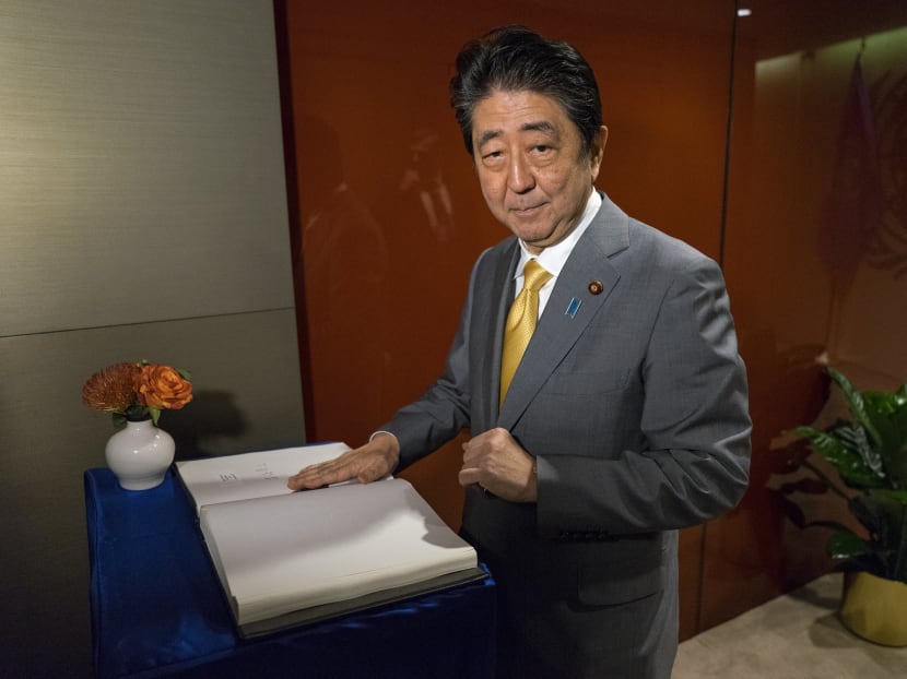 Japan's Prime Minister Shinzo Abe, seen here signing a guest book before a meeting with United Nations Secretary-General Antonio Guterres, may delay a target for reining in Japan’s ballooning debt. Photo: AP