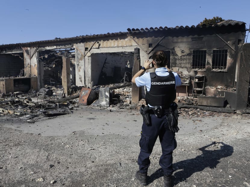 A policeman takes snapshots of the charred remains of burnt caravans and camper vans at a warehouse in La Londe-les-Maures on the French Riviera. Authorities ordered the evacuation of 10,000 people around the Riviera. Photo: AP
