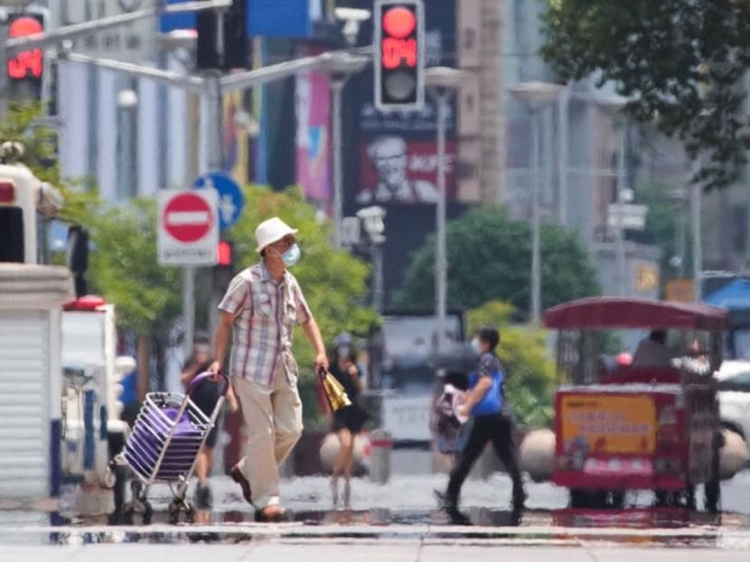 <p>A man wearing a face mask pulls a cart on a street amid a heatwave warning, following the Covid-19 outbreak in Shanghai, China on July 13, 2022.&nbsp;</p>
