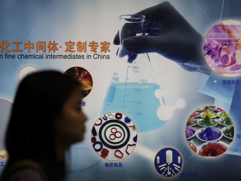 A woman walks by a display board of a Chinese chemical company in Shanghai. For a few thousand dollars, it’s easy to find Chinese companies that offer to export the powerful chemical carfentanil, which is so lethal it presents a potential terrorism threat. Photo: AP