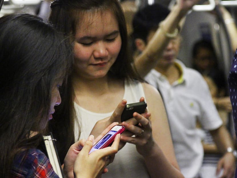 Commuters in an MRT train using their smartphones. TODAY file photo