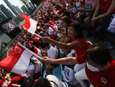 People waving the Singapore flag at the 2022 National Day Parade. 