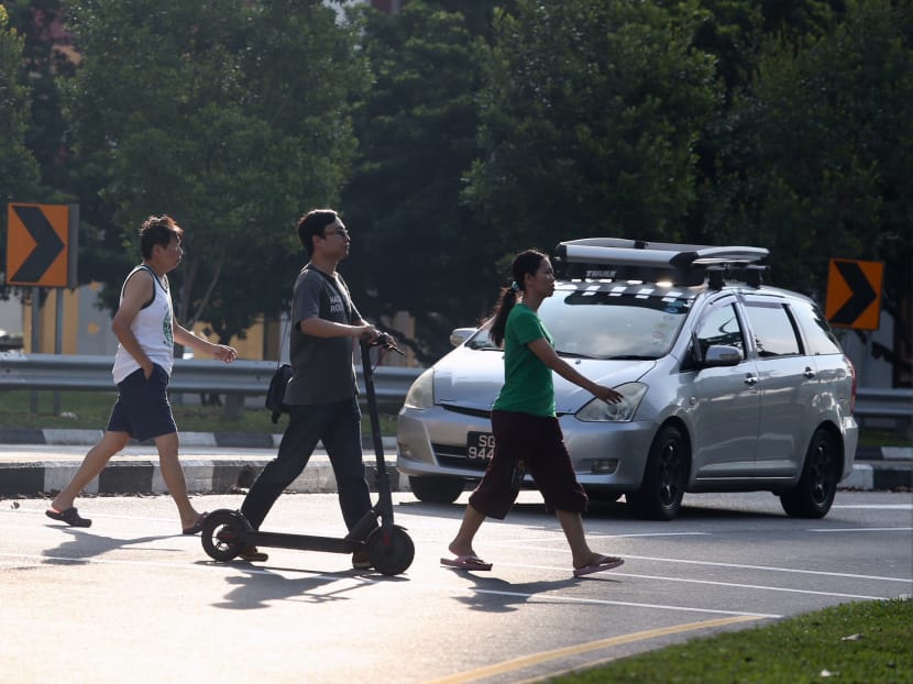 A man pushing his e-scooter while using the pedestrian crossing along Bishan Street 11. Photo: Koh Mui Fong/TODAY