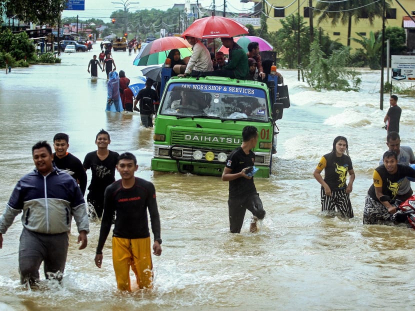People wade through a flooded street in Malaysia's northeastern town of Rantau Panjang, which borders Thailand, on Jan 3, 2017. Photo: AFP