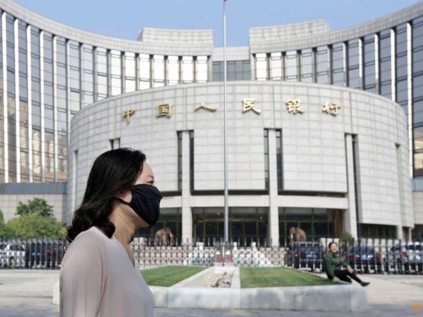 FILE PHOTO: A woman walks past the headquarters of the People's Bank of China (PBOC), the central bank, in Beijing, China September 28, 2018. REUTERS/Jason Lee/File Photo