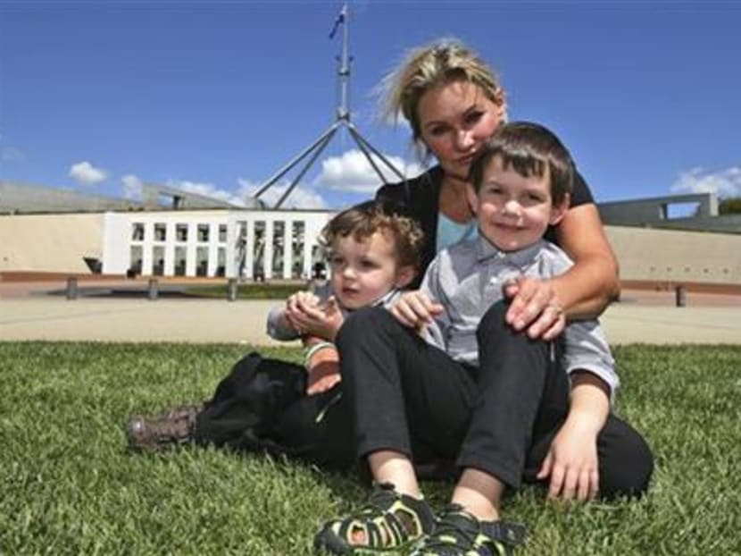 Ms Danica Weeks, who lost her husband on Malaysia Airlines Flight 370, poses for a photo with her sons Lincoln, 4, front right and Jack,1, outside the Australia Parliament House in Canberra, Australia, Thursday, March 5, 2015. Photo: AP
