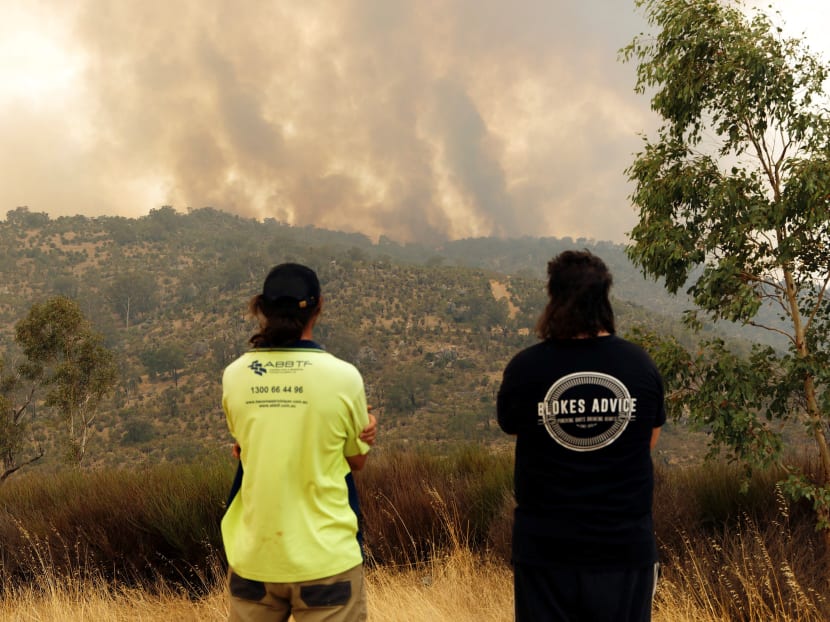 People look on as a fire driven by strong winds burns on a ridge in the suburb of Brigadoon in Perth on February 2, 2021, forcing emergency evacuations just days after the west coast city entered a coronavirus lockdown.