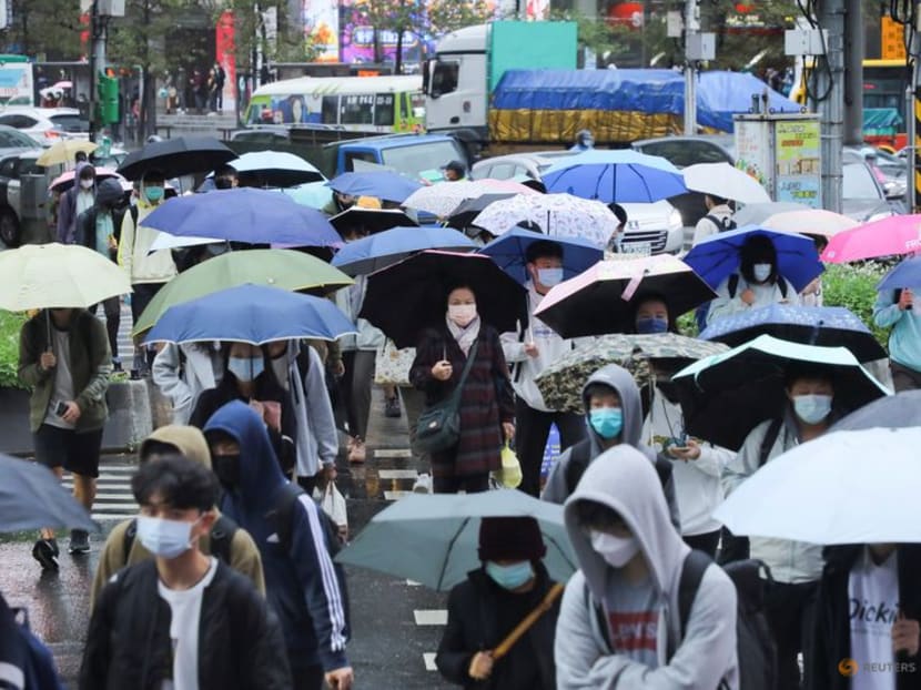 FILE PHOTO: People wearing face masks to prevent the spread of the coronavirus disease (COVID-19) and carrying umbrellas walk on the street during a rainy day in Taipei, Taiwan, November 26, 2021. REUTERS/Annabelle Chih