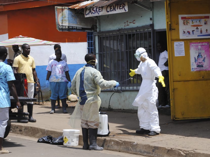 A member of a burial team sprays a colleague with chlorine disinfectant in Monrovia Oct 20, 2014. Photo: Reuters