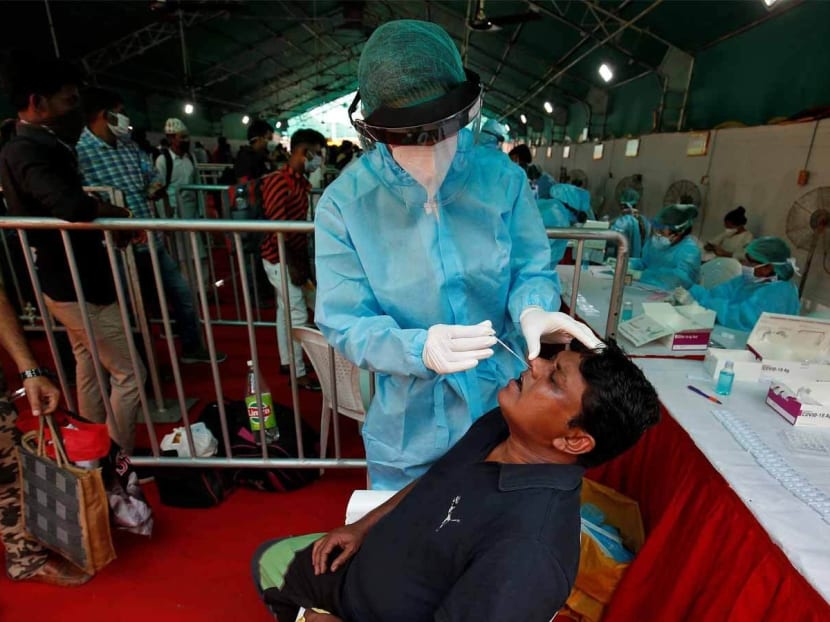 A healthcare worker collects a swab from a passenger for a rapid antigen test upon his arrival at a railway station, amidst the coronavirus disease outbreak, in Ahmedabad, India.