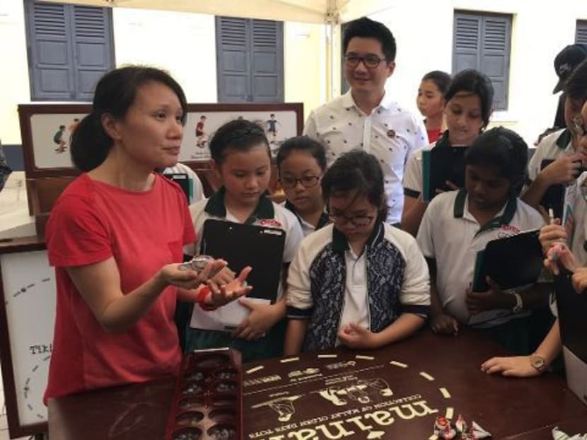 Students from Pei Tong Primary School learning to play traditional games, like congkak and batu seremban, to earn their Educator badge as part of the National Heritage Board's Heritage Explorers Programme. Photo: Channel NewsAsia
