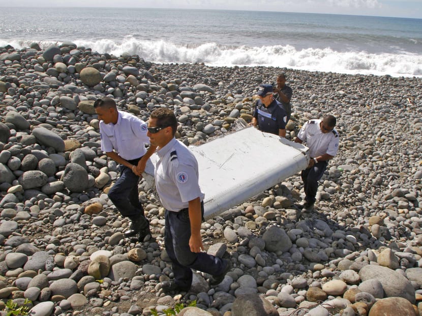 In this July 29, 2015, file photo, French police officers carry a piece of debris from a plane known as a "flaperon" on the shore of Saint-Andre, Reunion Island. Photo: AP