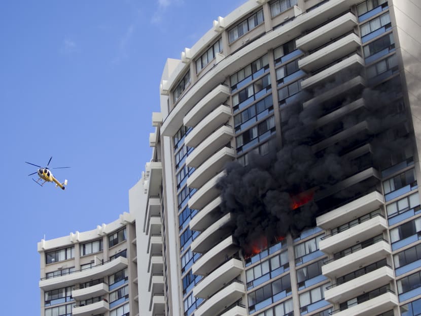 A Honolulu Fire Department helicopter flies near a fire burning on a floor at the Marco Polo apartment complex, Friday, July 14, 2107, in Honolulu. Photo: AP