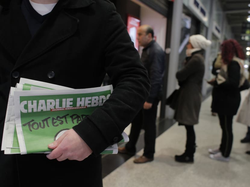A man leaves after buying Charlie Hebdo newspapers as people queue at a newsstand, in Paris, Jan 14, 2015. Photo: AP