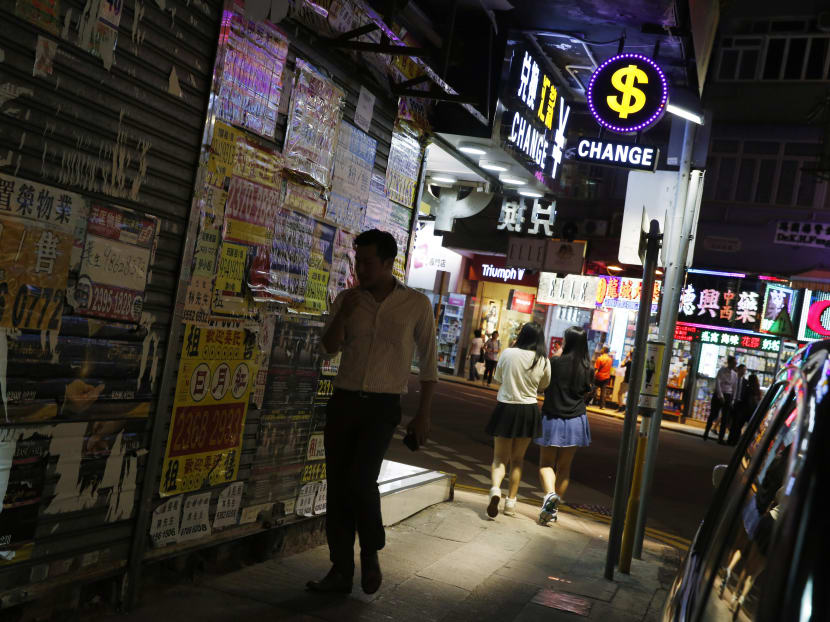 People walk near a dollar sign outside a money exchange shop in Hong Kong, Oct 8, 2015. Photo: AP