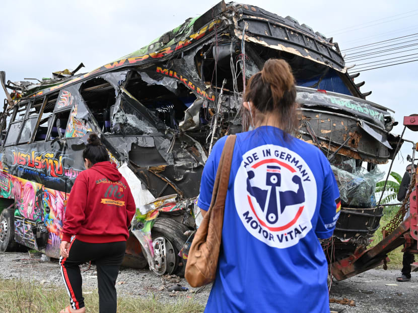 People stand next to the wreckage of an bus involved in a deadly collision with a train after it was lifted off the tracks by Khlong Kwaeng Klan railway station in Chachoengsao province, east of the Thai capital Bangkok, on Oc 11, 2020.