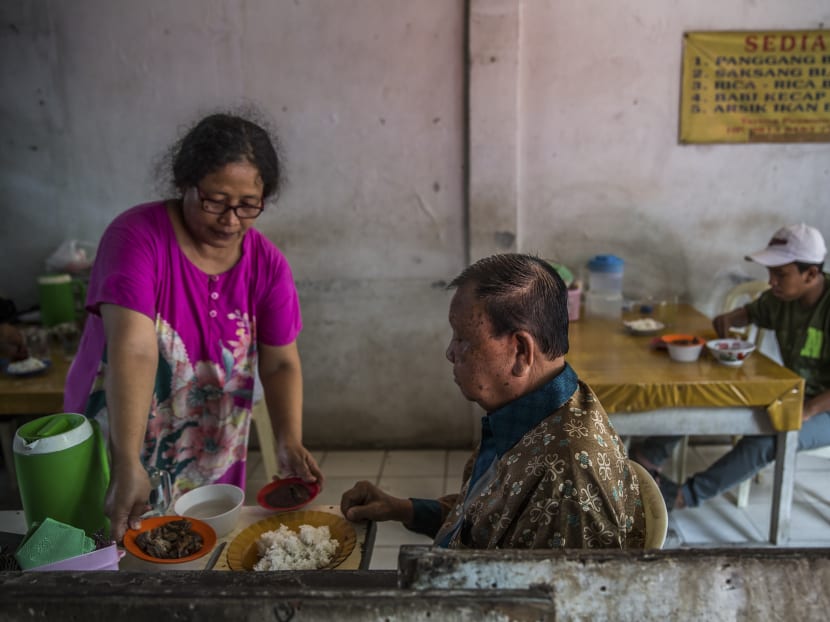 A woman serves a dog meat dish to customers at Betlehem Restaurant in Jakarta, where the meat is newly affordable — and popular. Photo: The New York Times