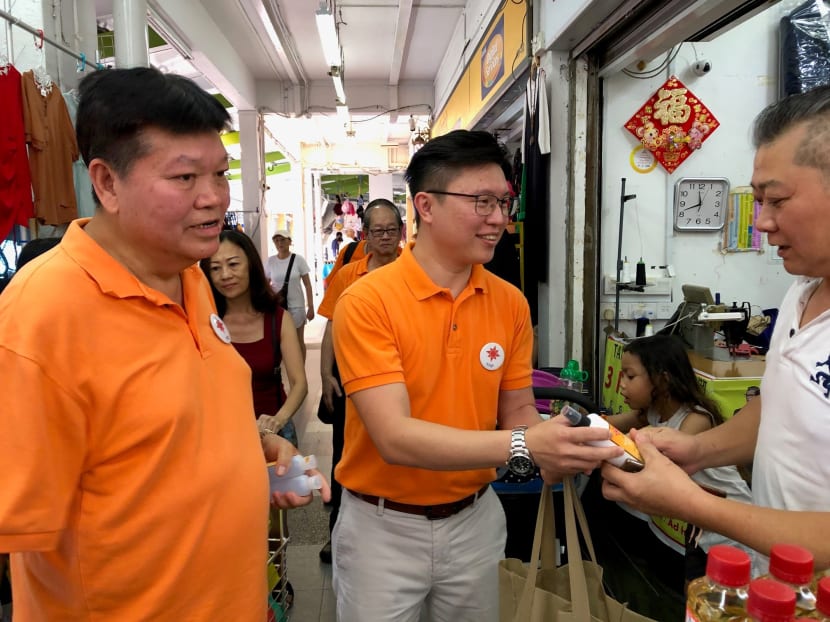 National Solidarity Party secretary-general Spencer Ng (centre) and party member Sebastian Teo (left) giving out hand sanitiser to shopkeepers during a walkabout along Tampines Street 81 on March 22, 2020.