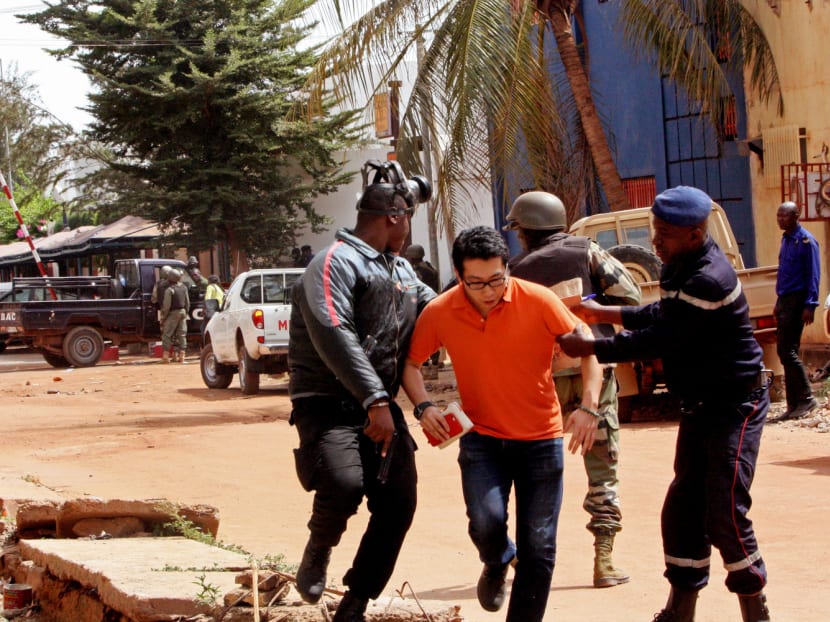 Mali troopers helping a man (centre) flee from the Radisson Blu hotel after it was stormed by gunmen. Photo: AP
