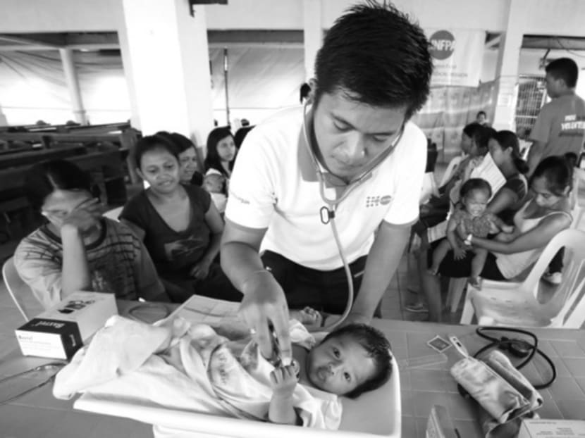 A United Nations Population Fund volunteer nurse checking a baby during a medical mission for typhoon Haiyan survivors in Palo, Leyte, in the Philippines, in 2013. Photo: Reuters
