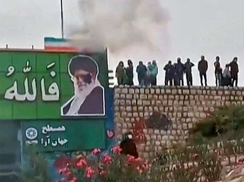 This image grab from a UGC video posted on Nov 3, 2022, reportedly shows protesters throwing a small explosive device at a banner depicting the Islamic Republic's Supreme Leader Ayatollah Ali Khamenei, as a large crowd enters the district of Fuladshahr near the central city of Isfahan.
This image grab from a UGC video posted on Nov 3, 2022, reportedly shows protesters throwing a small explosive device at a banner depicting the Islamic Republic's Supreme Leader Ayatollah Ali Khamenei, as a large crowd enters the district of Fuladshahr near the central city of Isfahan.